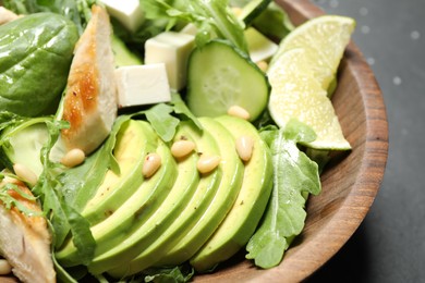 Photo of Delicious salad with chicken, arugula and avocado in bowl on table, closeup