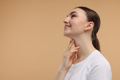 Photo of Smiling woman touching her chin on beige background. Space for text