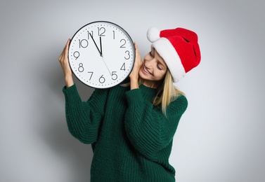 Woman in Santa hat with clock on white background. New Year countdown