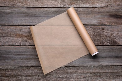 Photo of Roll of baking paper on wooden table, top view