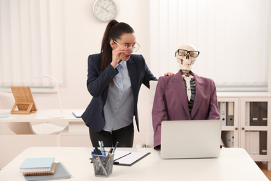Young woman working with skeleton in office