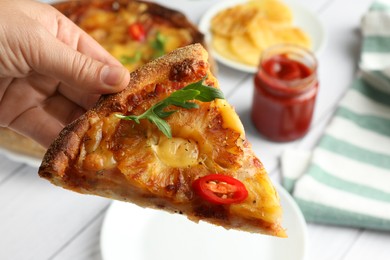 Photo of Woman holding piece of delicious Hawaiian pizza with pineapple, closeup