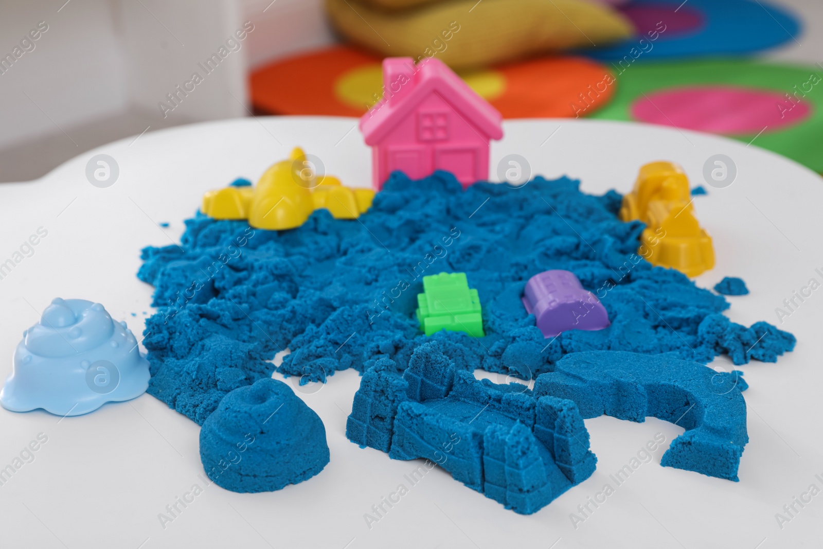 Photo of Bright kinetic sand and toys on white table indoors