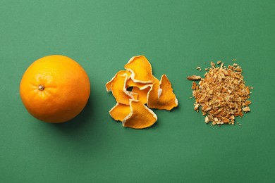 Photo of Dried orange zest seasoning, peel and fruit on green background, flat lay