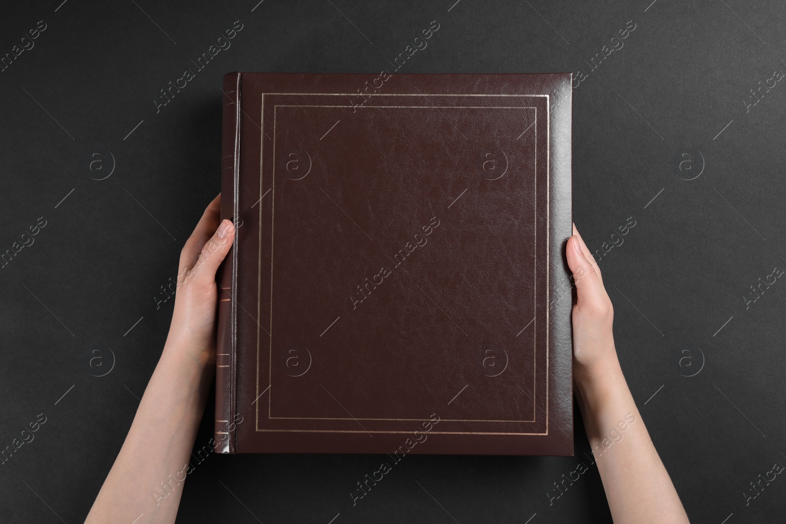Photo of Woman with photo album at black table, top view