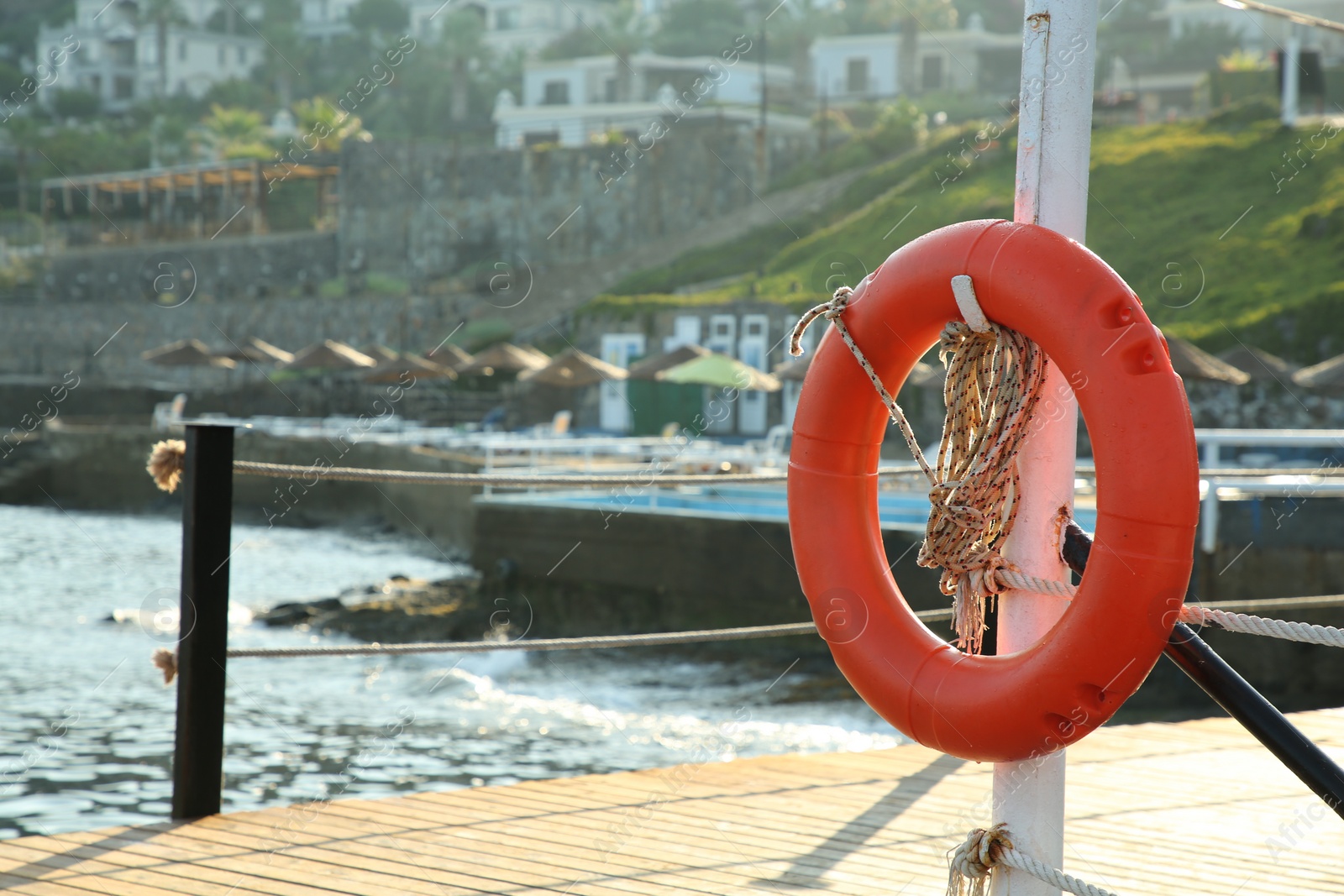 Photo of Orange lifebuoy hanging on post near sea, space for text