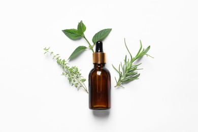 Photo of Bottle of essential oil and different herbs on white background, flat lay