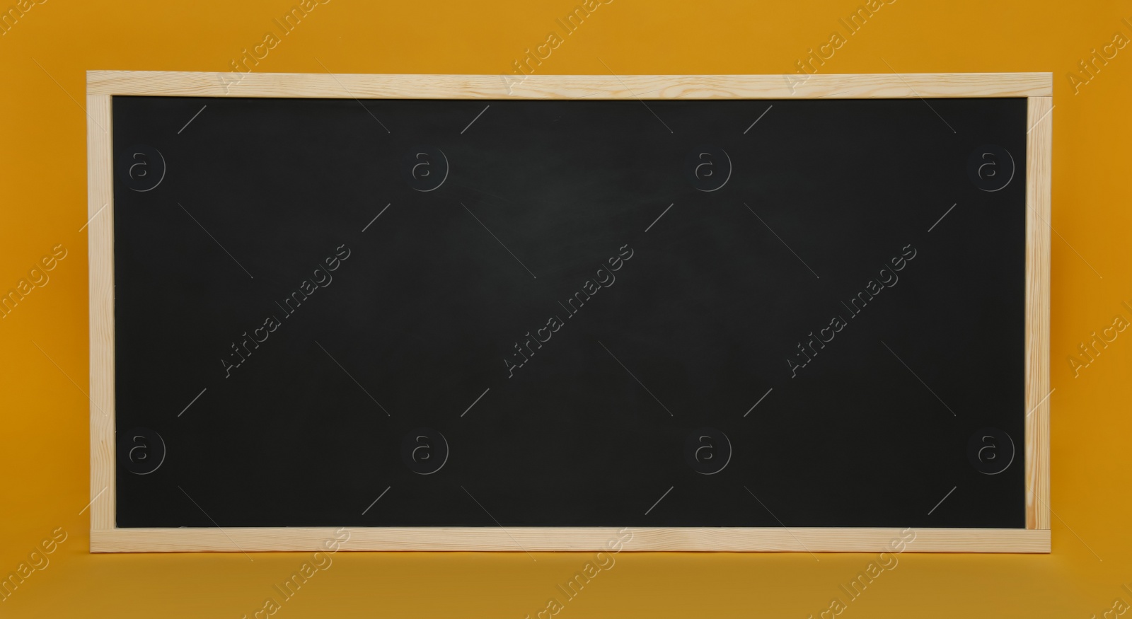 Photo of Clean black chalkboard on orange background. School equipment
