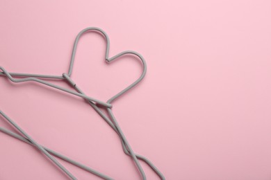 Two hangers on pink background, top view. Space for text