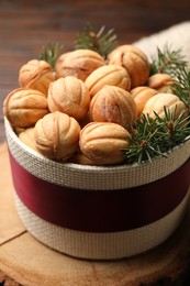 Bowl of delicious nut shaped cookies and fir tree branches on wooden table