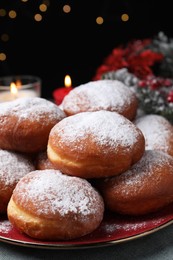 Photo of Delicious sweet buns on table against black background with blurred lights, closeup