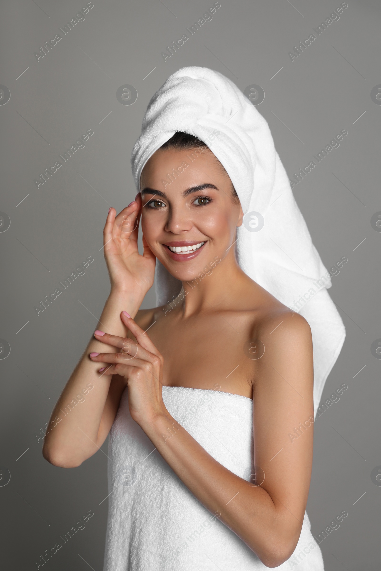 Photo of Beautiful young woman with towels on grey background