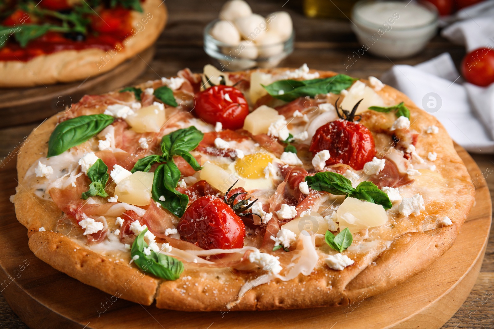 Photo of Pita pizza with prosciutto, pineapple, grilled tomatoes and egg on wooden tray, closeup