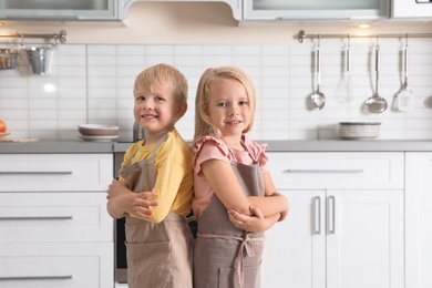 Cute little kids wearing aprons in kitchen