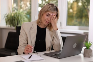Overwhelmed woman sitting at table in office