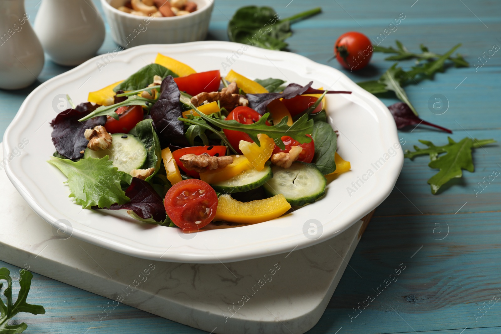 Photo of Tasty fresh vegetarian salad on light blue wooden table, closeup