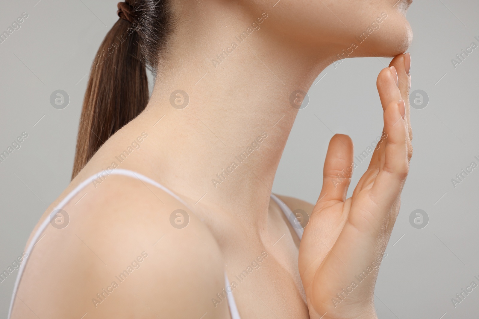 Photo of Woman touching her chin on grey background, closeup