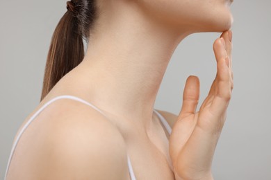 Woman touching her chin on grey background, closeup