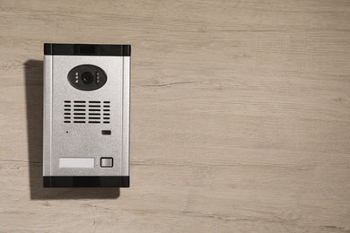 Photo of Modern intercom system with camera on wooden background, top view. Space for text