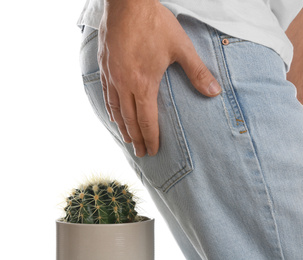 Photo of Man sitting down on cactus against white background, closeup. Hemorrhoid concept