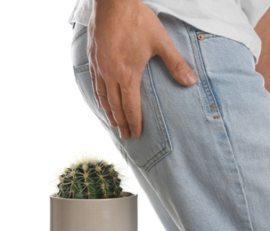 Man sitting down on cactus against white background, closeup. Hemorrhoid concept