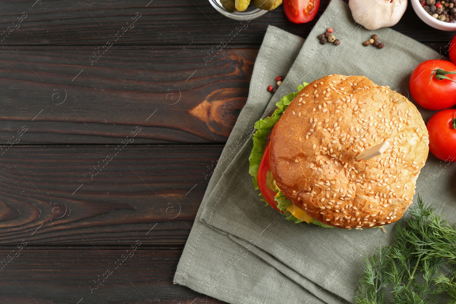 Photo of Delicious vegetarian burger and ingredients on wooden table, top view. Space for text