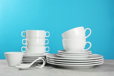 Photo of Set of clean dishware on grey table against light blue background