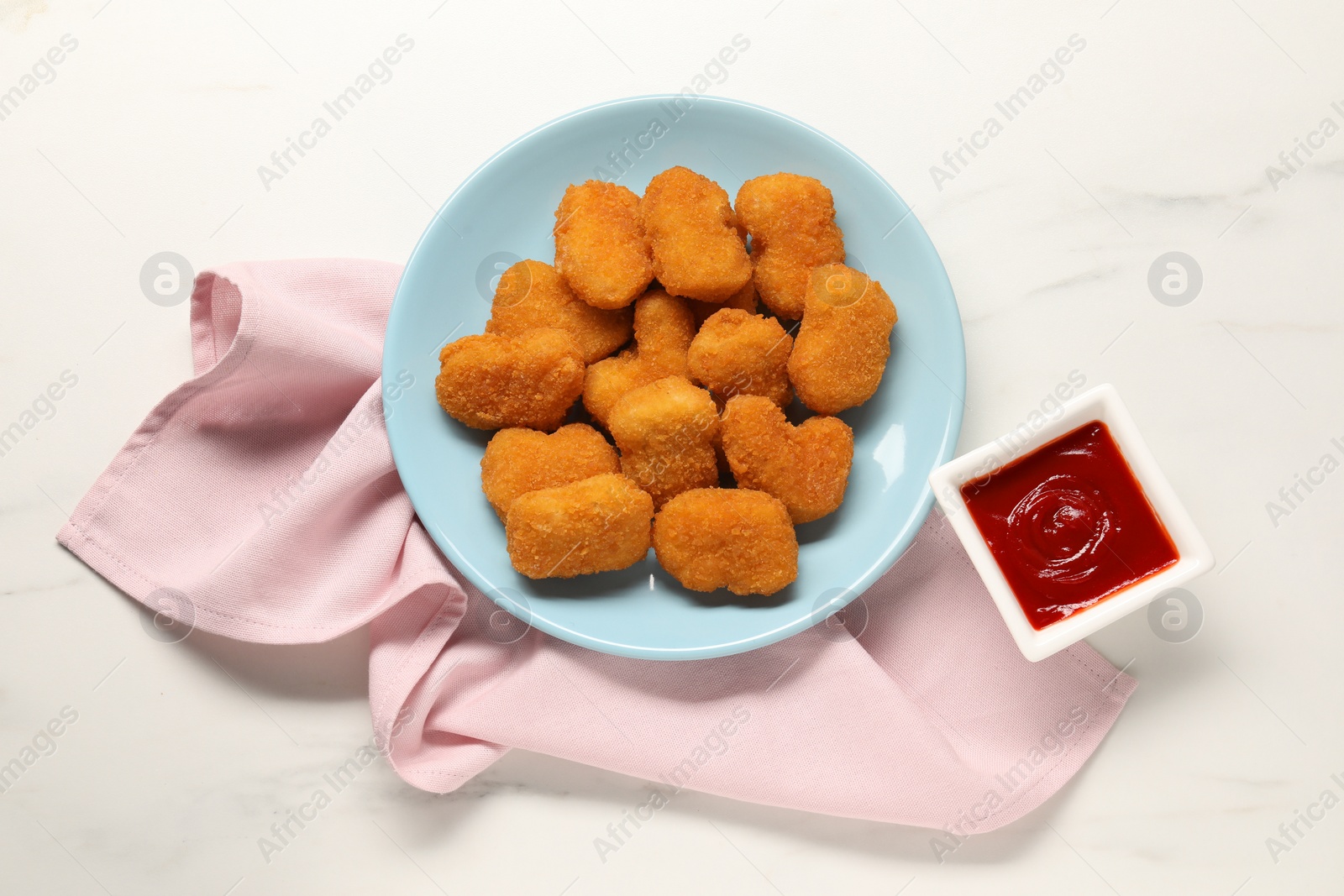 Photo of Tasty ketchup and chicken nuggets on marble table, flat lay