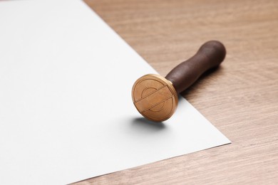 One stamp tool and sheet of paper on wooden table, closeup. Space for text