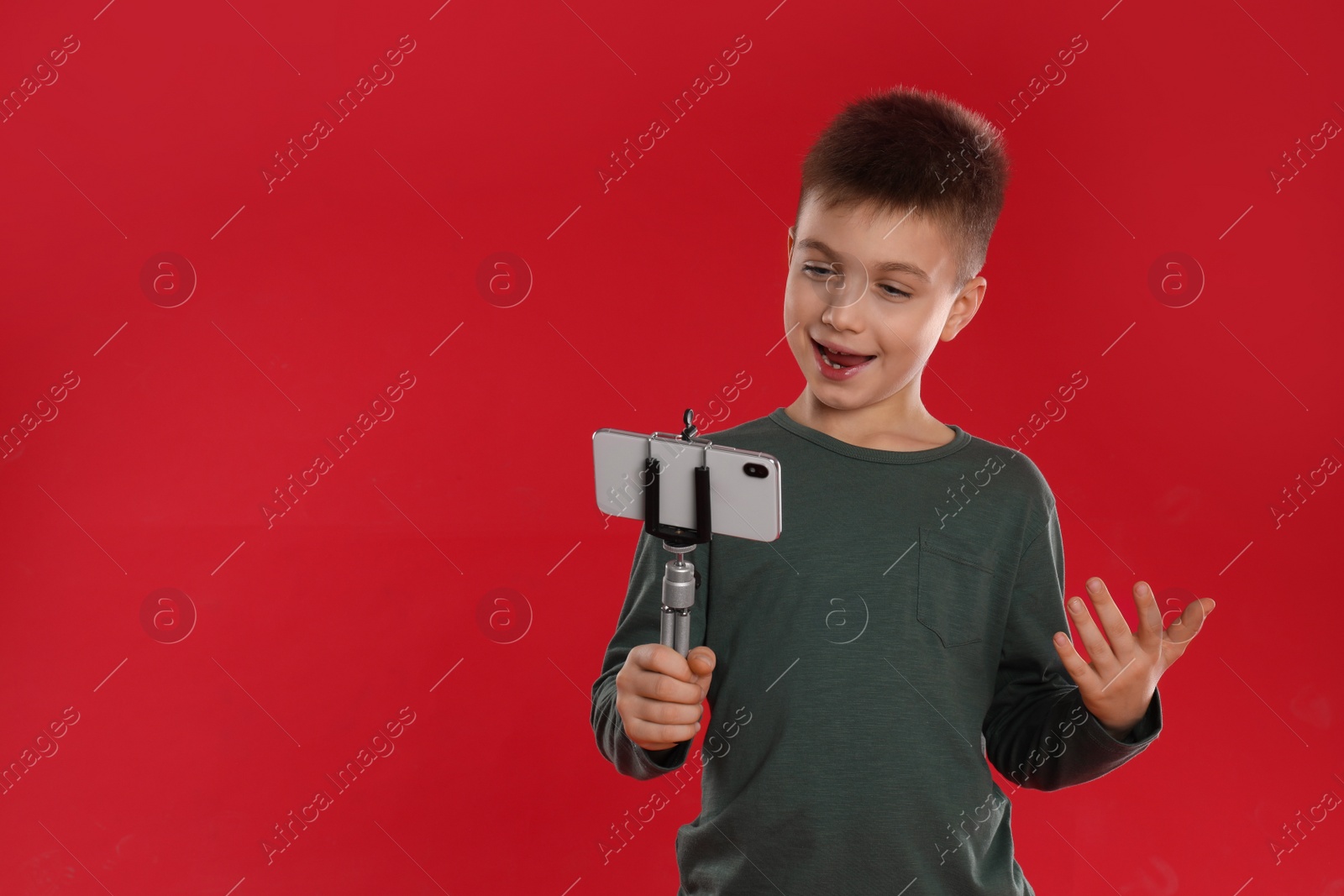 Photo of Cute little blogger recording video on red background