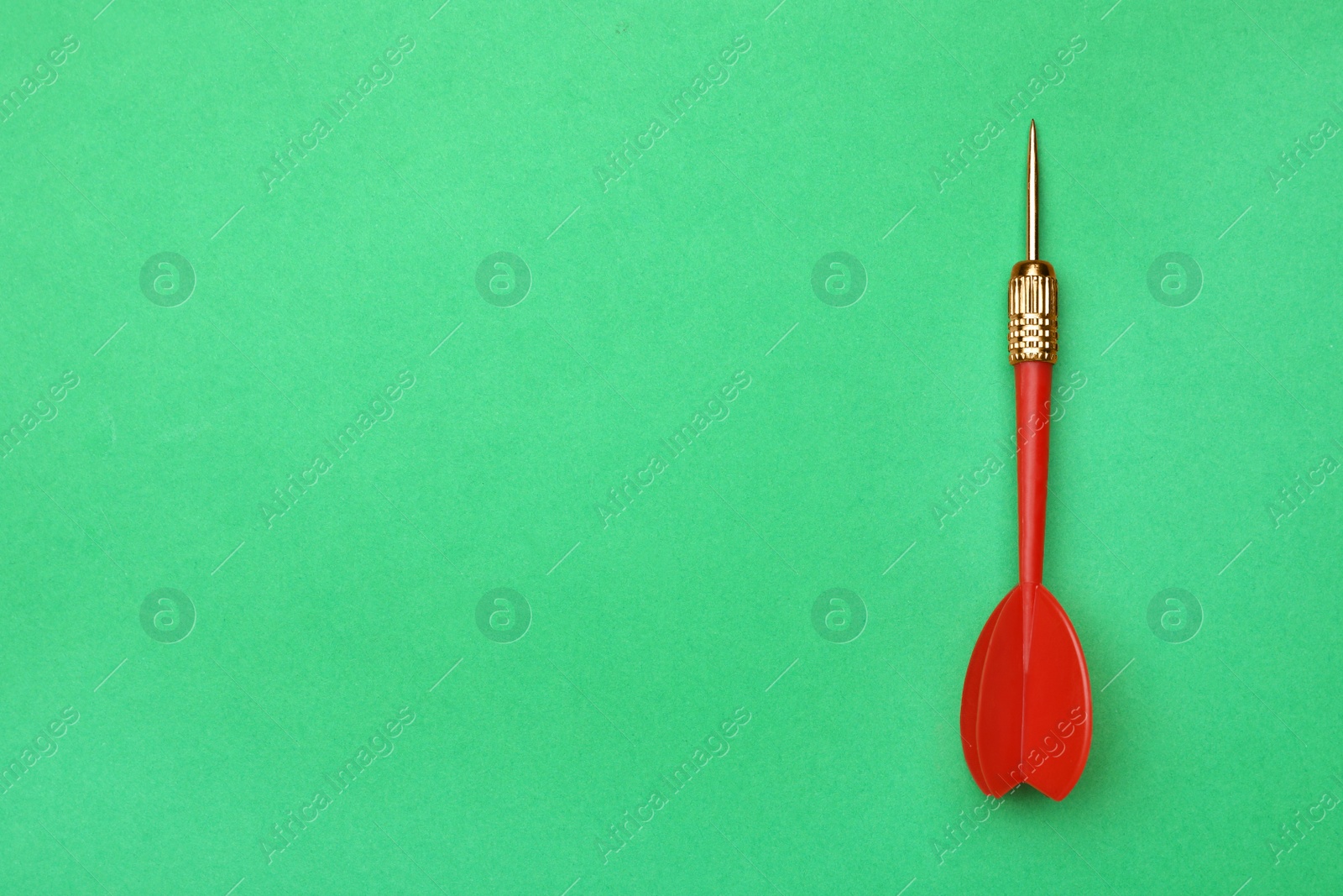 Photo of Red dart arrow on green background, top view with space for text