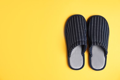Photo of Pair of stylish slippers on yellow background, top view. Space for text