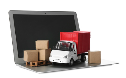 Photo of Laptop, truck model and carton boxes on white background. Courier service