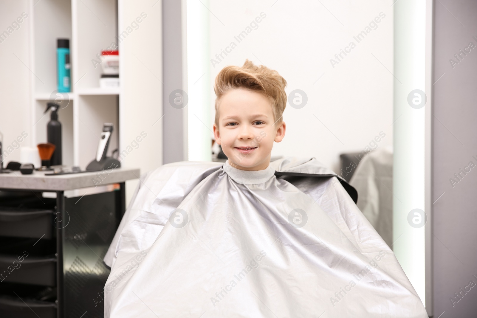 Photo of Cute little boy in hairdressing salon