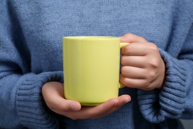 Woman holding yellow mug of drink, closeup