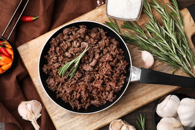 Fried ground meat in frying pan and products on wooden table, flat lay