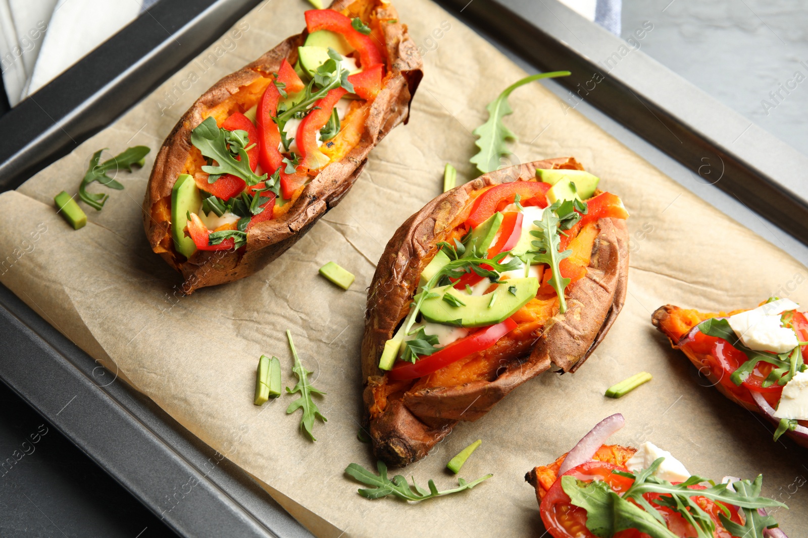 Photo of Baking sheet with stuffed sweet potatoes on table, closeup