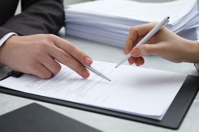 Photo of Woman signing document at table in office, closeup