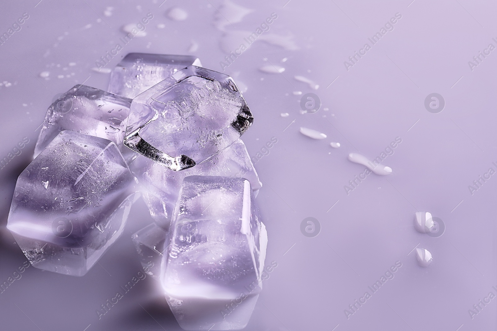 Photo of Transparent ice cubes on color mirror surface. Space for text