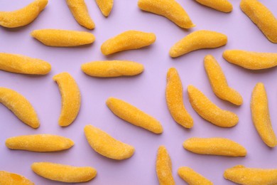 Photo of Tasty jelly candies in shape of banana on lilac background, flat lay