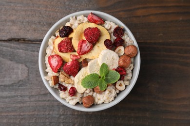 Photo of Oatmeal with freeze dried fruits, nuts and mint on wooden table, top view