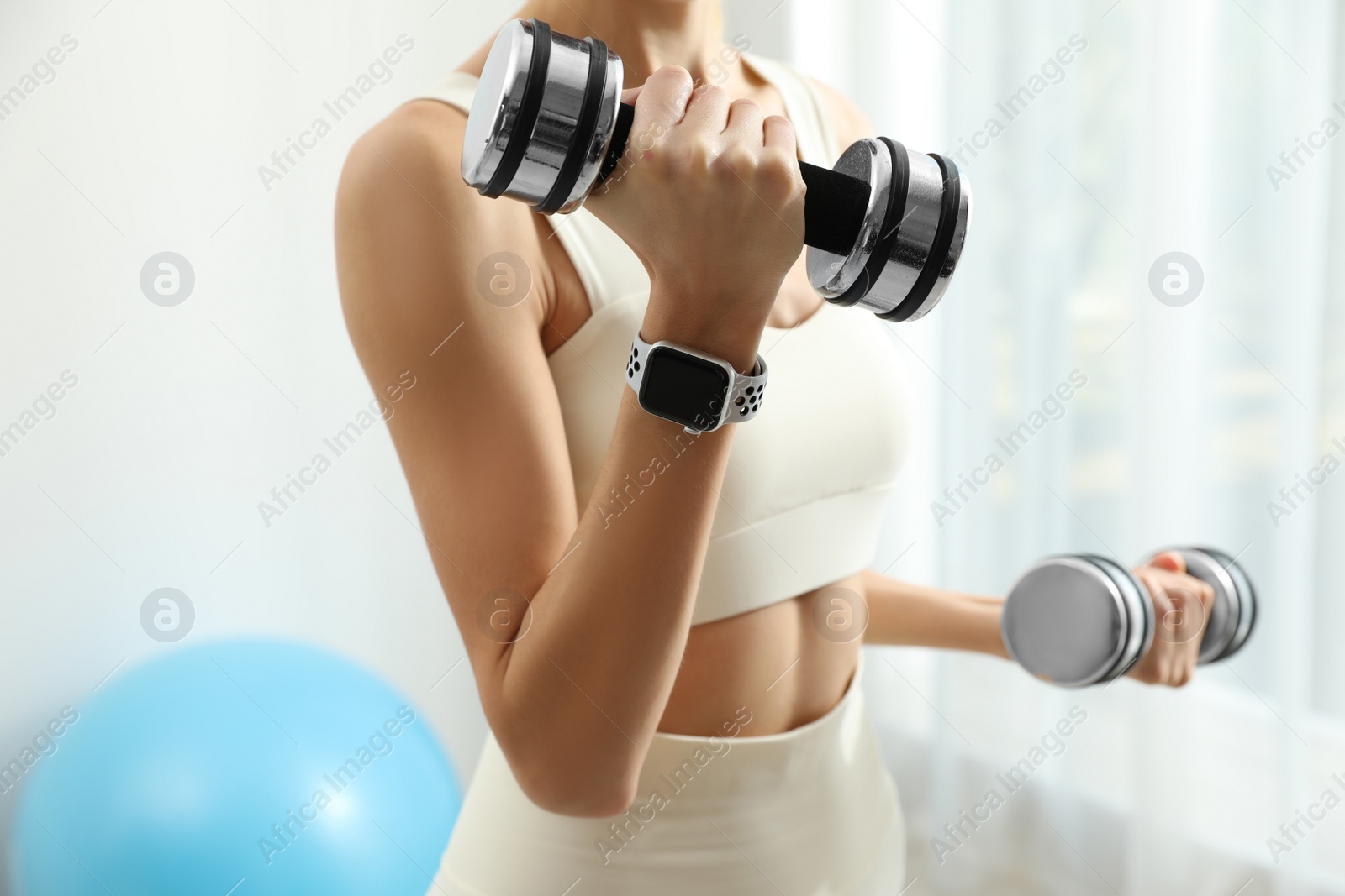 Photo of Young woman wearing smart watch during training indoors, closeup