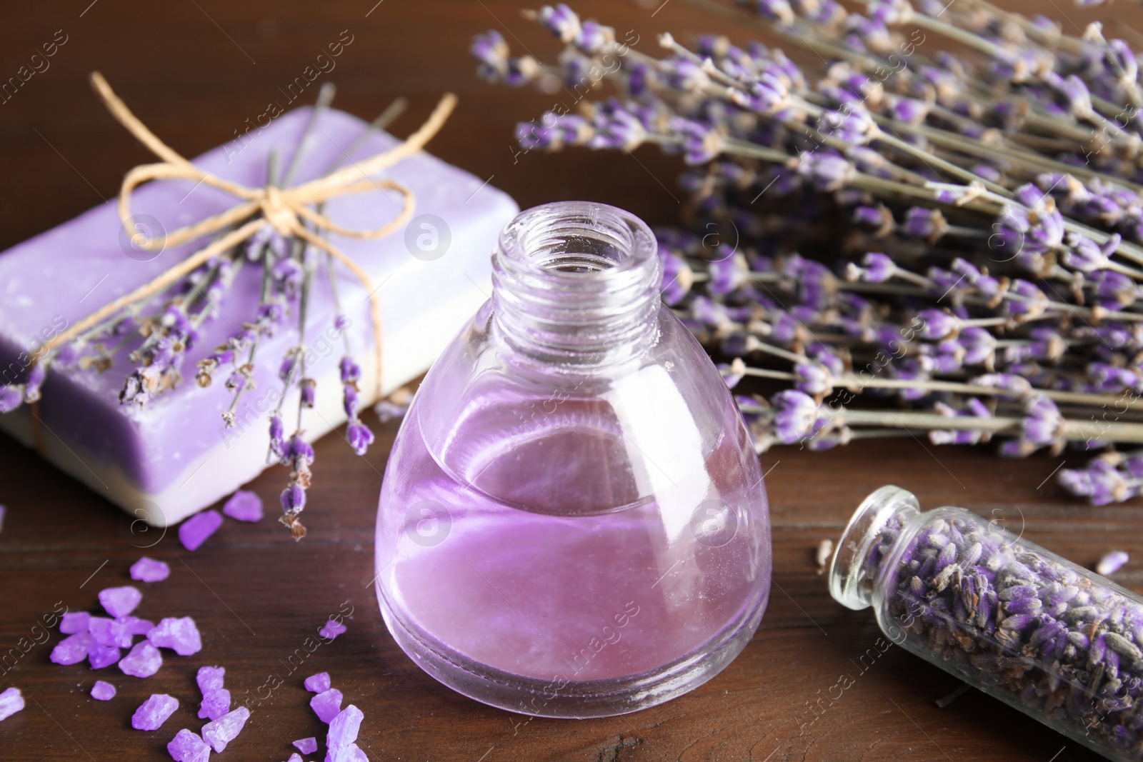 Photo of Bottle with aromatic lavender oil on wooden table