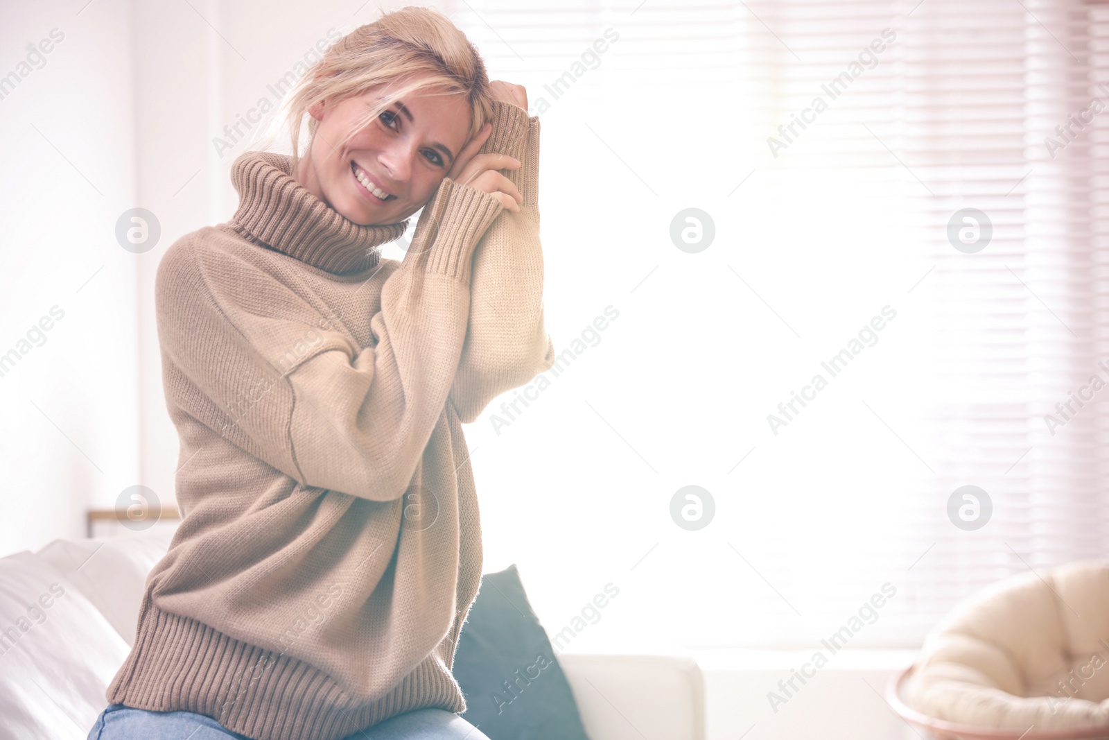 Photo of Happy woman in stylish sweater in light room