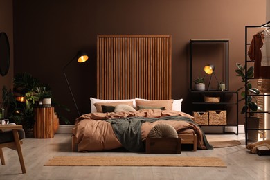 Stylish room interior with large bed near brown wall