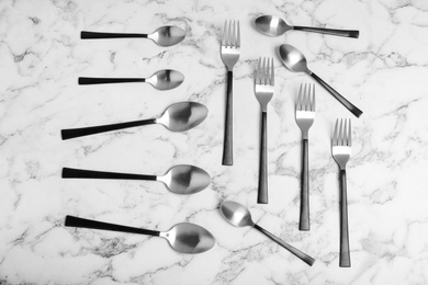 Flat lay composition with steel cutlery on white marble table