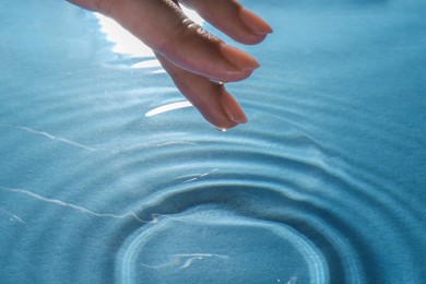 Woman touching clear water, closeup. Making ripples