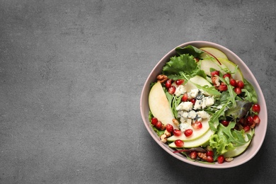 Tasty salad with pear slices and pomegranate seeds on grey table, top view. Space for text