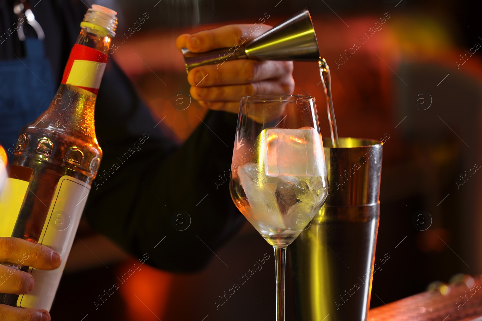 Photo of Bartender making fresh alcoholic cocktail against blurred background, closeup