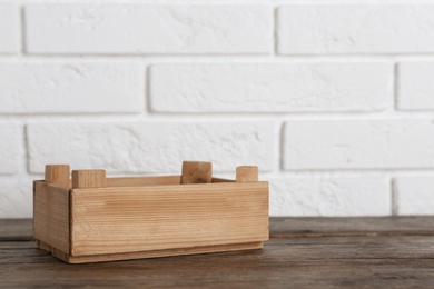 Wooden crate on table near brick wall. Space for text